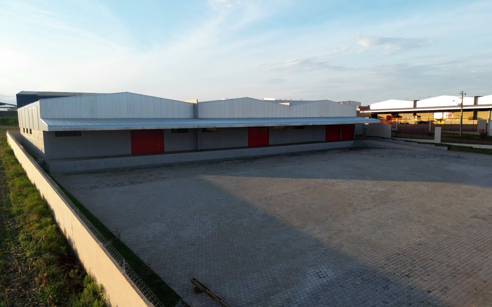 Pátio pavimentado do Armazém 2 com os três galpões independentes ao fundo